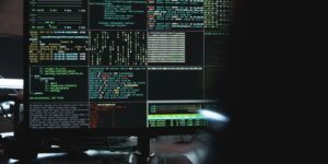 Close-up of a computer monitor displaying cyber security data and code, indicative of system hacking or programming.